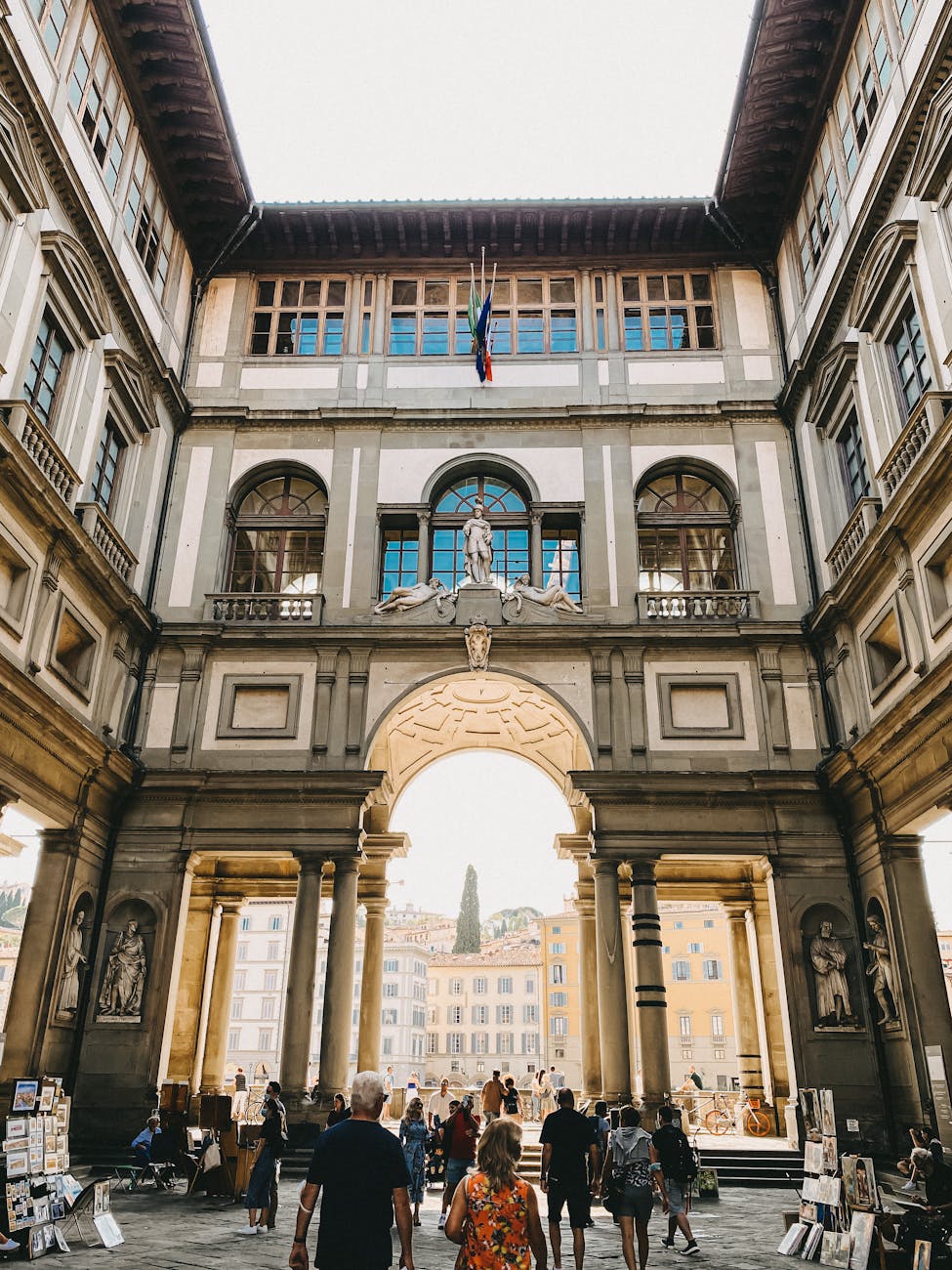 people walking through an archway in a courtyard